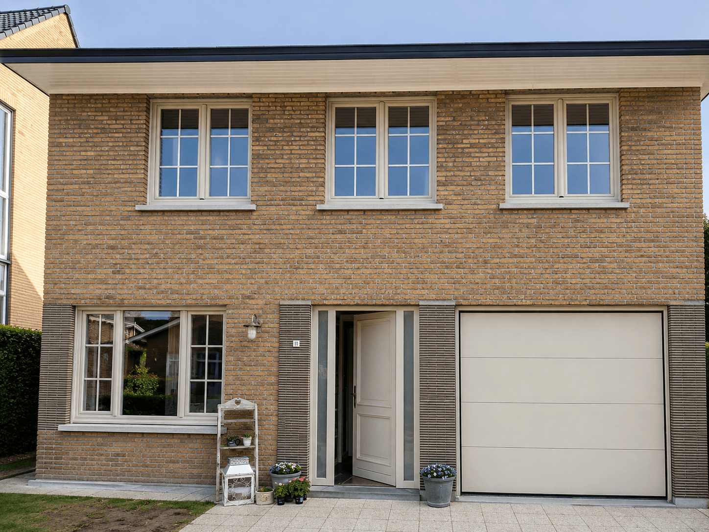 Bakstenen gezinswoning met ramen, voordeur en garagepoort - realisatie Thimaco