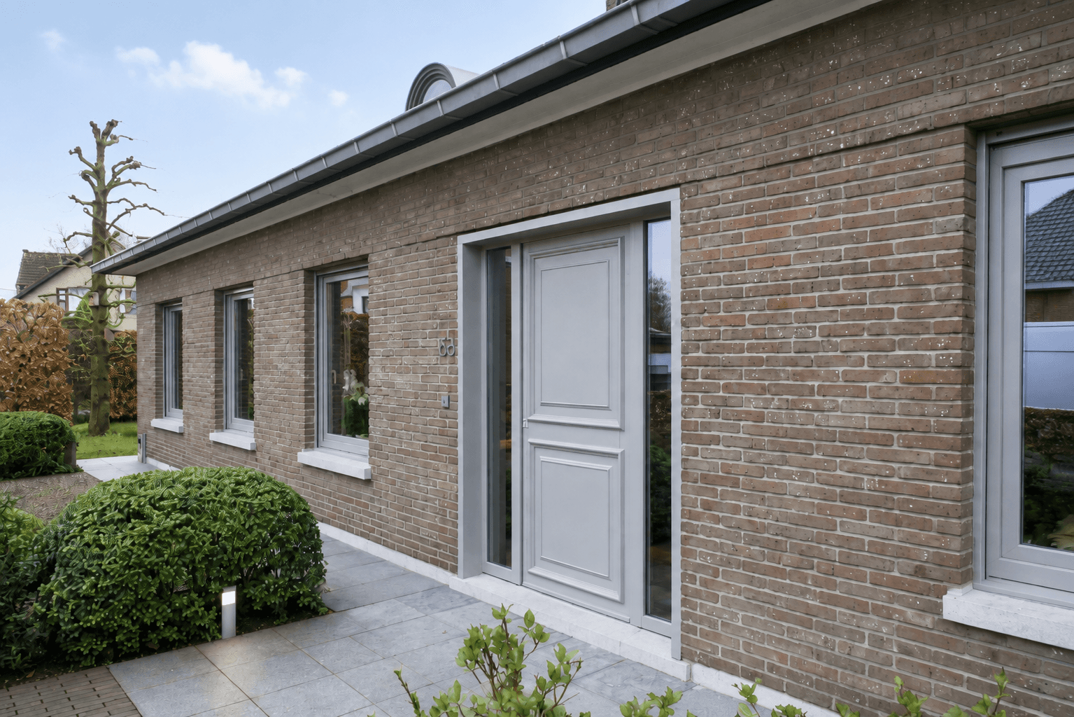 Bakstenen woning met grijze ramen en voordeur - realisatie Thimaco